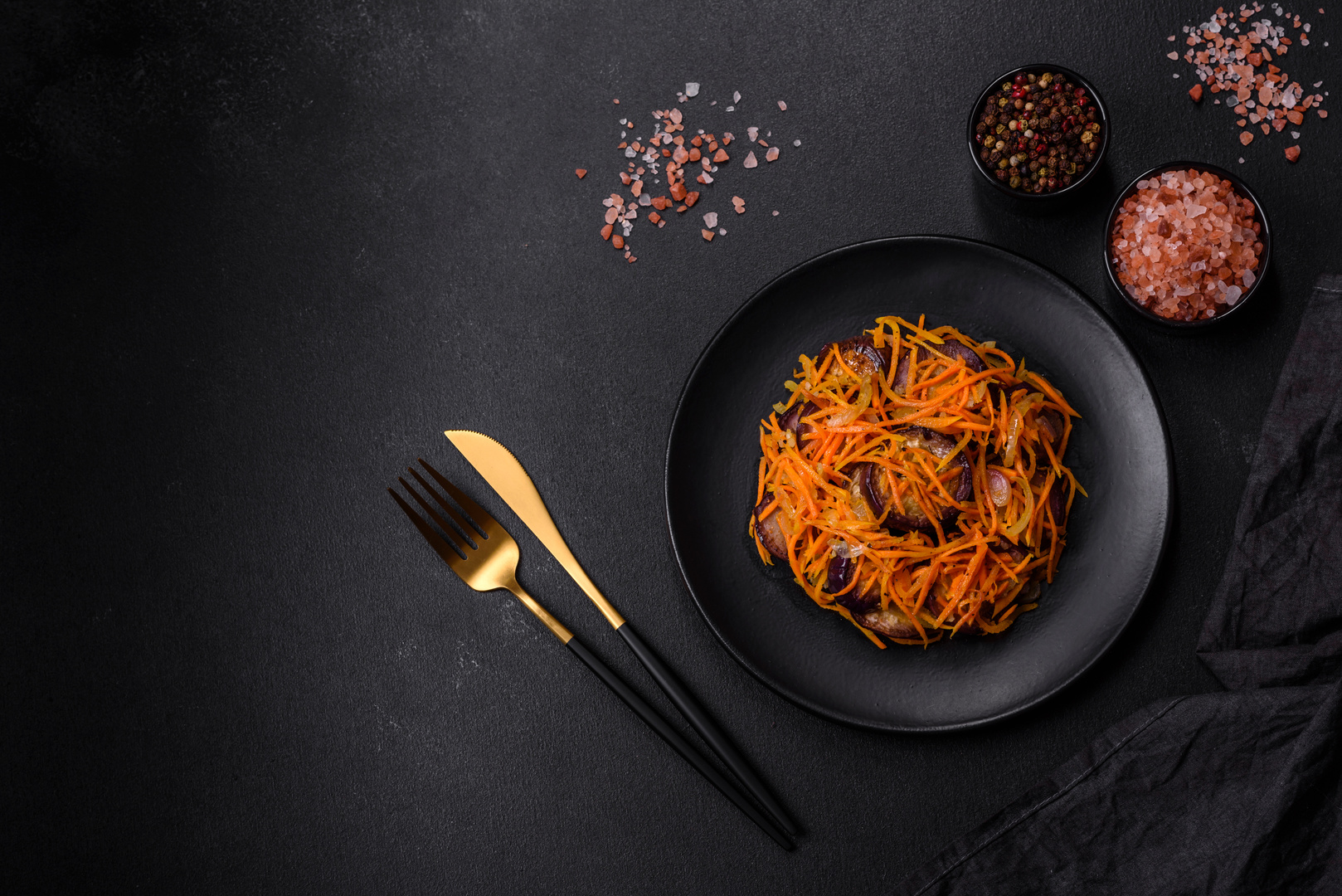 Korean salad with eggplant, carrots, garlic, spices and herbs on a dark concrete background